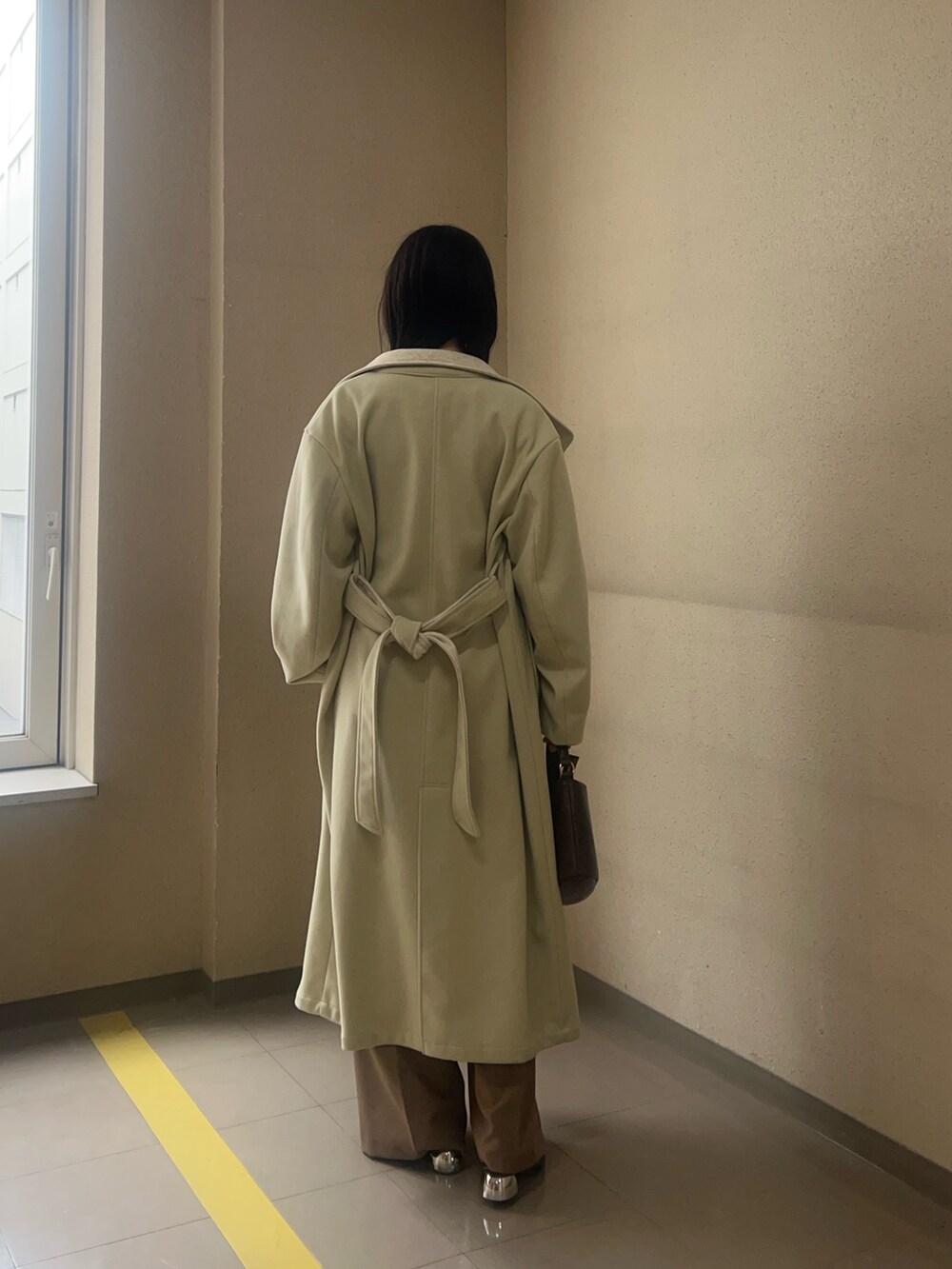 グリーン系のチェスターコート、ブラウン系のハンドバッグ、ブラウン系のその他パンツを着用したレディースの秋コーディネートの3枚目の写真