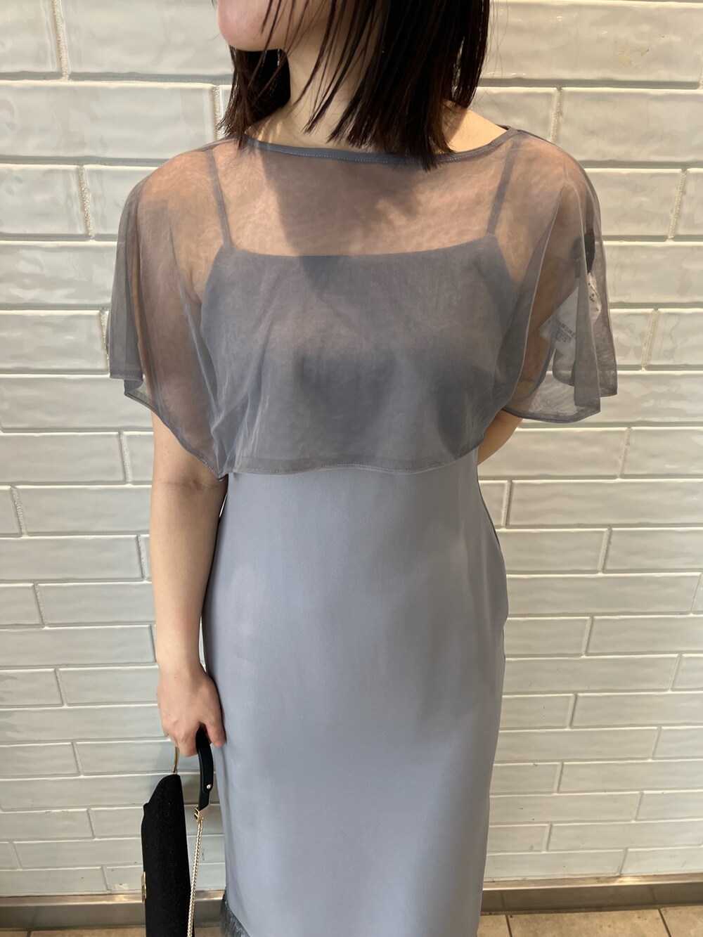 パープル系のドレス、ブラック系のクラッチバッグ、ブラック系のパンプスを着用したレディースの秋コーディネートの4枚目の写真