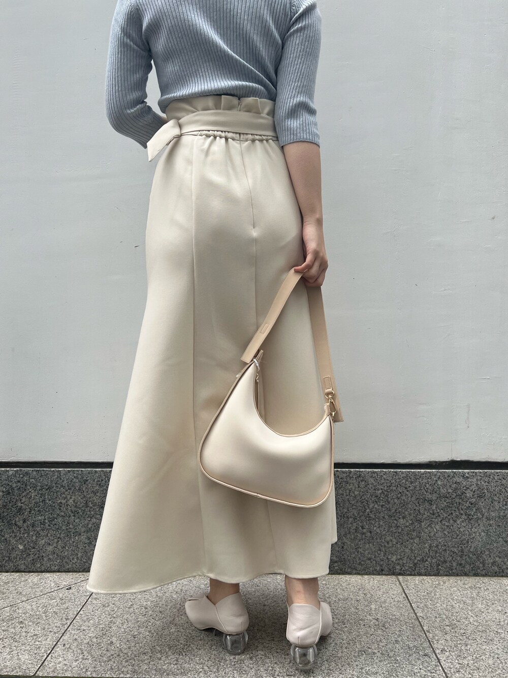 ホワイト系のパンプス、ベージュ系のハンドバッグ、ブルー系のニット/セーターを着用したレディースの春コーディネートの7枚目の写真