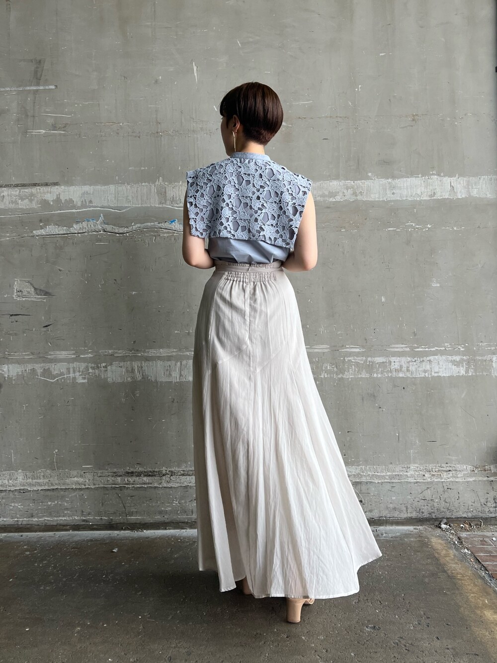 ベージュ系のサンダル、ホワイト系のハンドバッグ、グレー系のスカートを着用したレディースの夏コーディネートの2枚目の写真