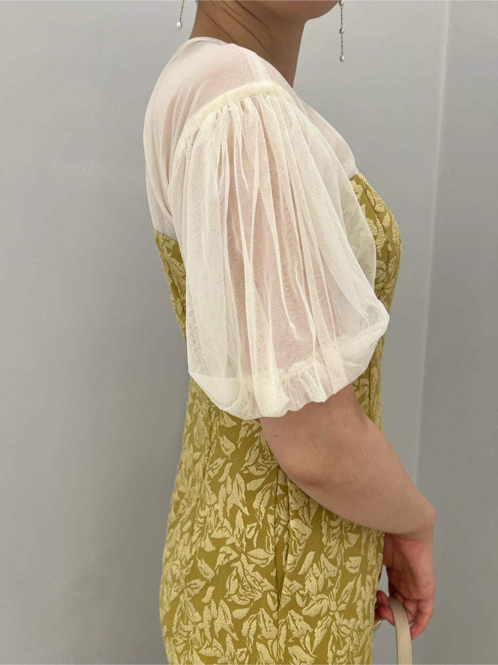 ベージュ系のパンプス、イエロー系のドレス、ベージュ系のクラッチバッグを着用したレディースの秋コーディネートの7枚目の写真