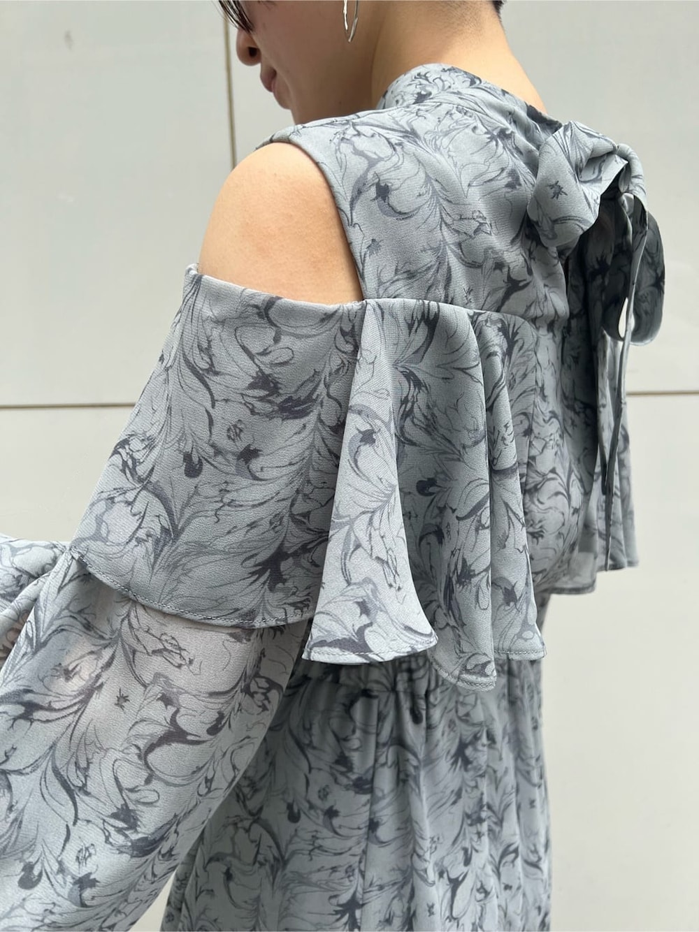 ベージュ系のハンドバッグ、ブルー系のワンピース、シルバー系のピアス（両耳用）を着用したレディースの夏コーディネートの6枚目の写真