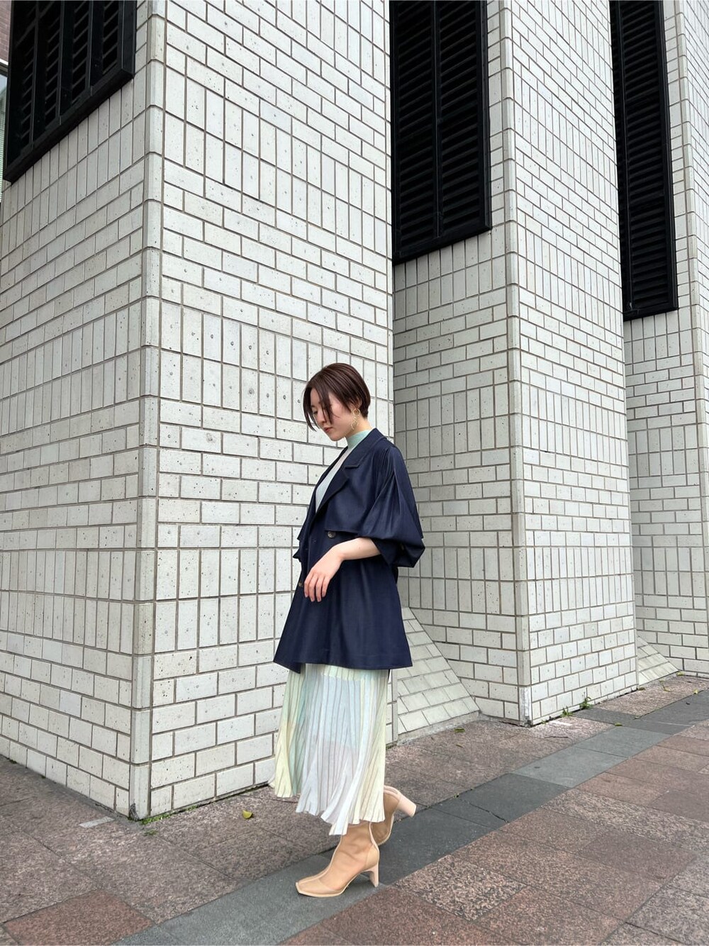 ベージュ系のブーツ、ブルー系のトレンチコート、グリーン系のワンピースを着用したレディースの春コーディネートの3枚目の写真