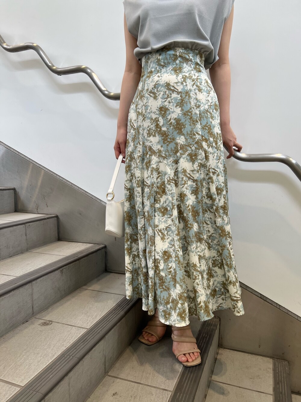 ベージュ系のサンダル、ホワイト系のハンドバッグ、グリーン系のスカートを着用したレディースの夏コーディネートの6枚目の写真