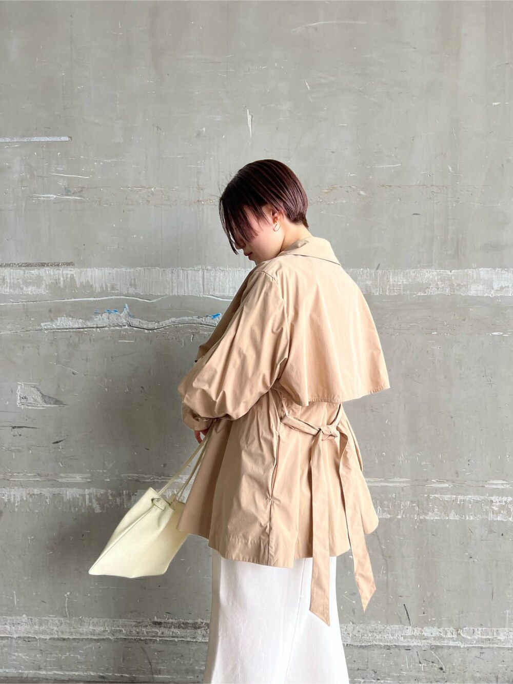 ホワイト系のハンドバッグ、ホワイト系のワンピース、ベージュ系のブーツを着用したレディースの冬コーディネートの5枚目の写真