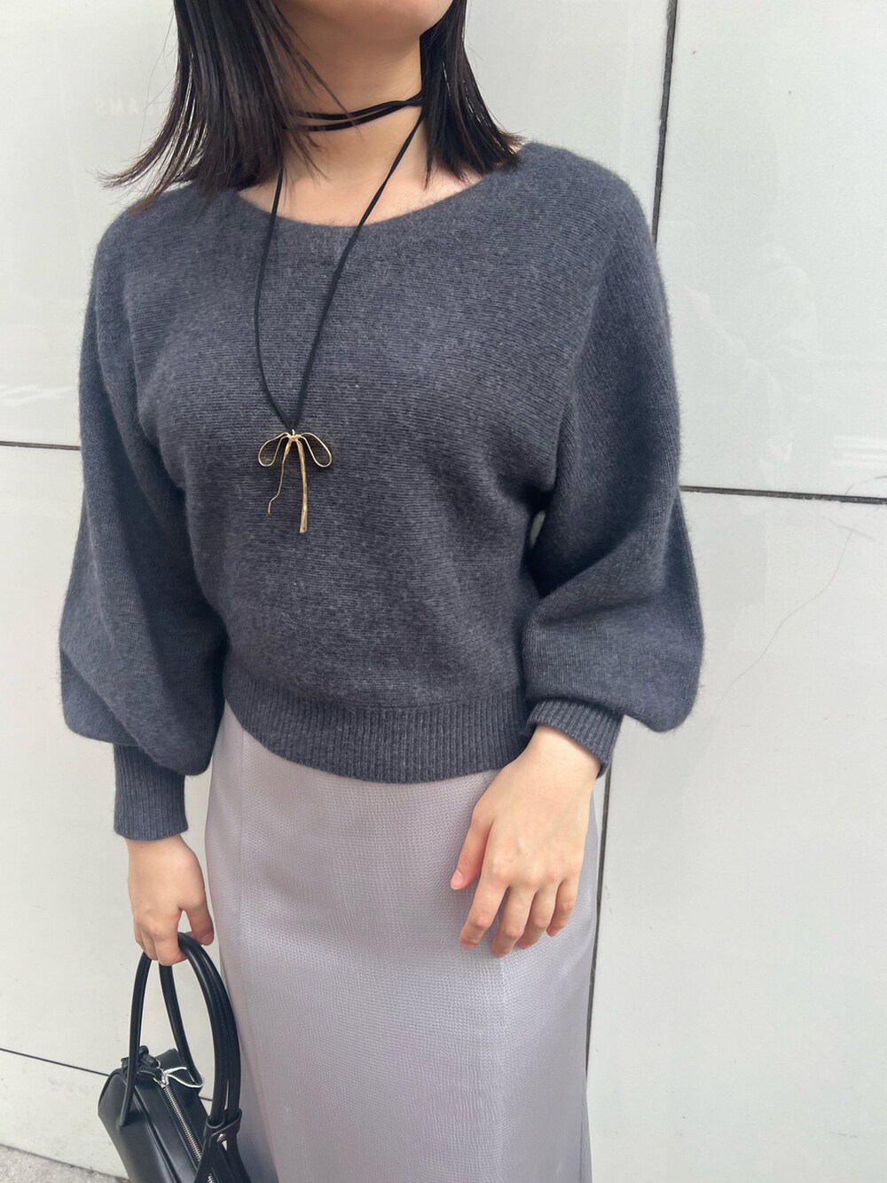 グレー系のニット/セーター、グレー系のカーディガン/ボレロ、ブラック系のスカートを着用したレディースの秋コーディネートの3枚目の写真