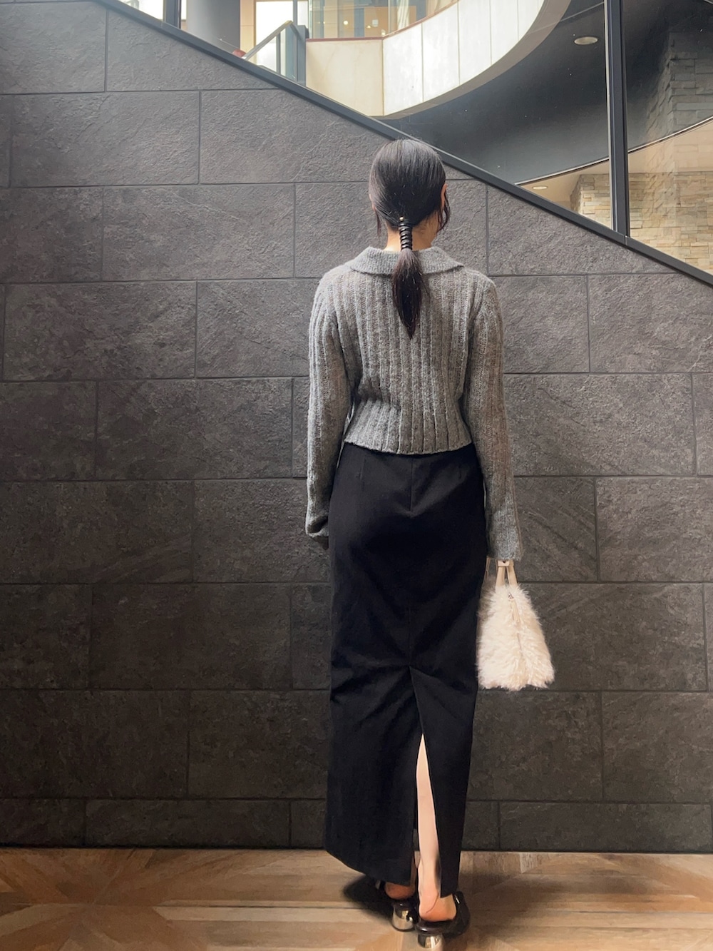 ブラック系のスカート、グレー系のニット/セーター、ブラウン系のパンプスを着用したレディースの秋コーディネートの3枚目の写真