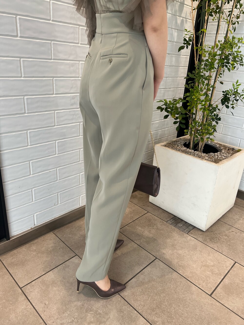 シルバー系のパンプス、シルバー系のハンドバッグ、グリーン系のパンツドレスを着用したレディースの春コーディネートの10枚目の写真