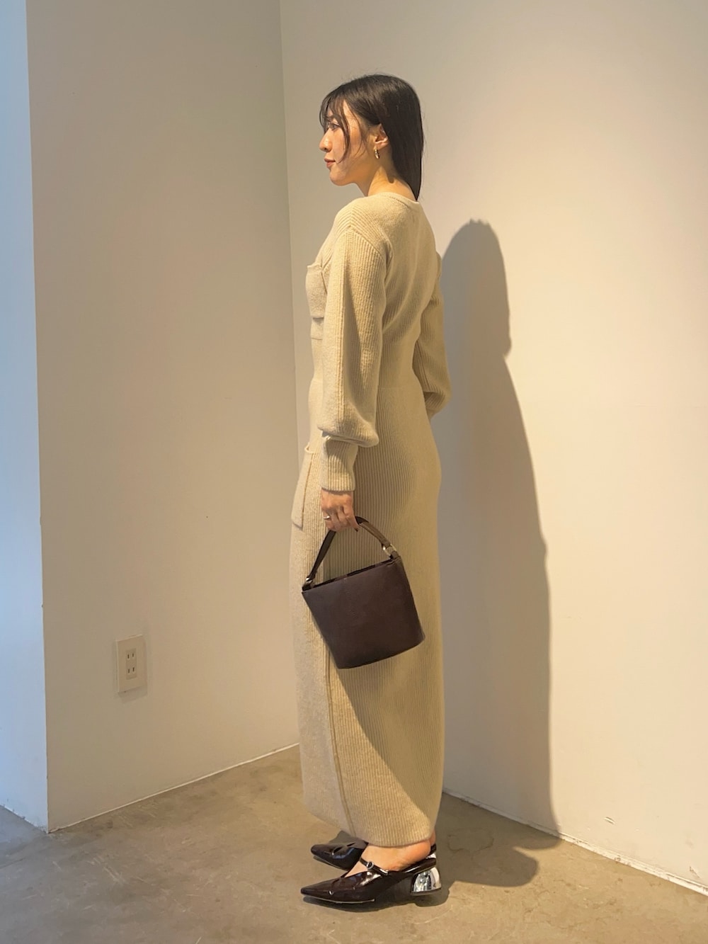 ベージュ系のワンピース、ブラウン系のハンドバッグ、ブラウン系のパンプスを着用したレディースの秋コーディネートの2枚目の写真