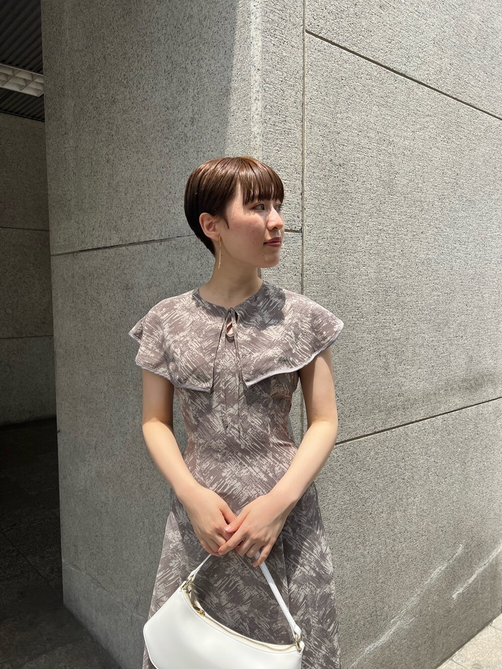 ホワイト系のハンドバッグ、ベージュ系のサンダル、グレー系のワンピースを着用したレディースの夏コーディネートの4枚目の写真