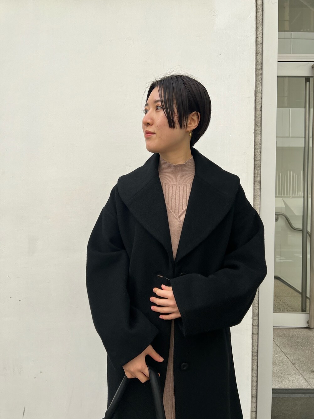 レッド系のブーツ、ブラック系のハンドバッグ、ベージュ系のワンピースを着用したレディースの冬コーディネートの3枚目の写真