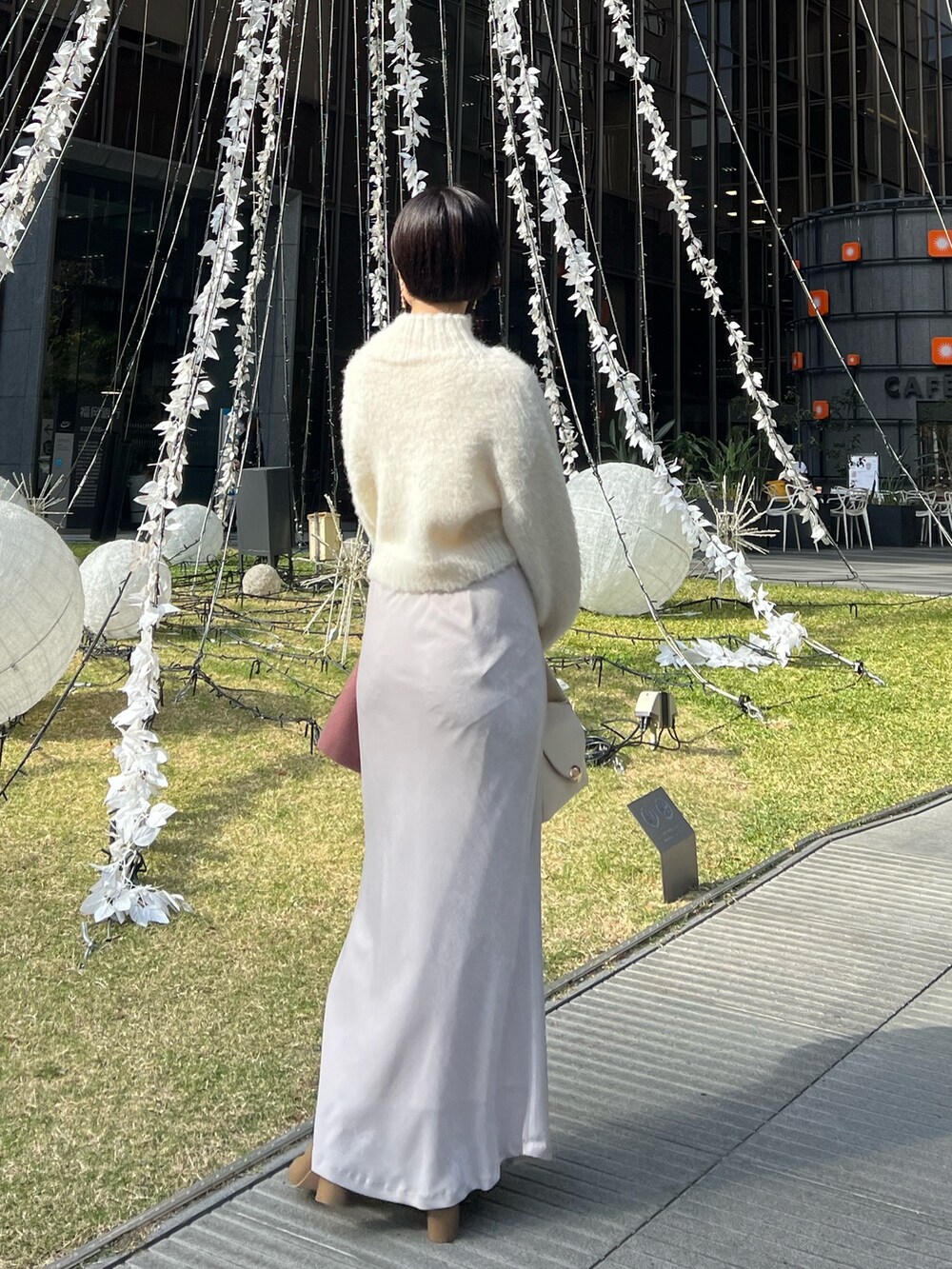 ホワイト系のスカート、ホワイト系のハンドバッグ、ピンク系のカーディガン/ボレロを着用したレディースの冬コーディネートの4枚目の写真