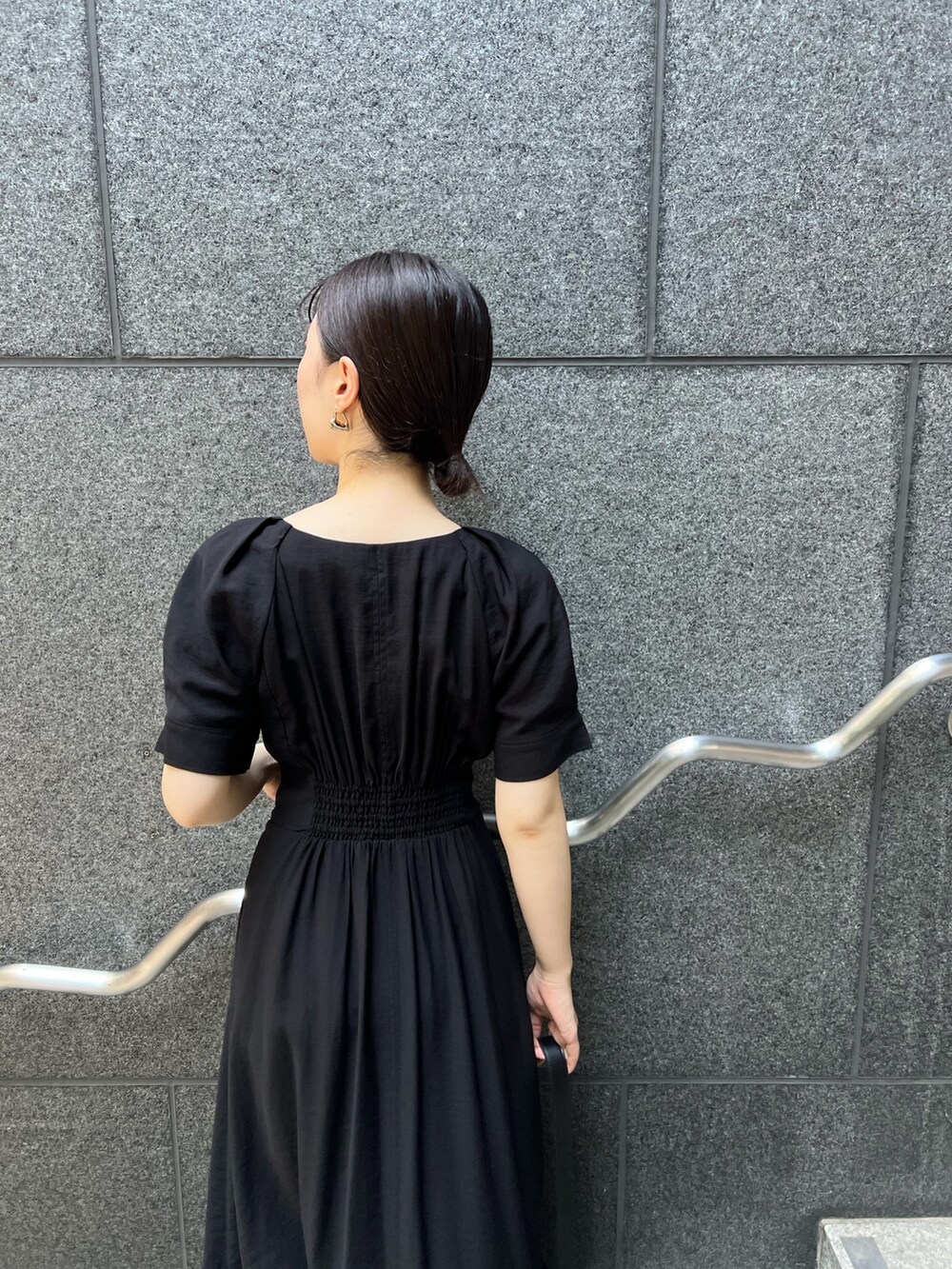 ブラック系のワンピース、ブラック系のショルダーバッグ、シルバー系のパンプスを着用したレディースの夏コーディネートの5枚目の写真