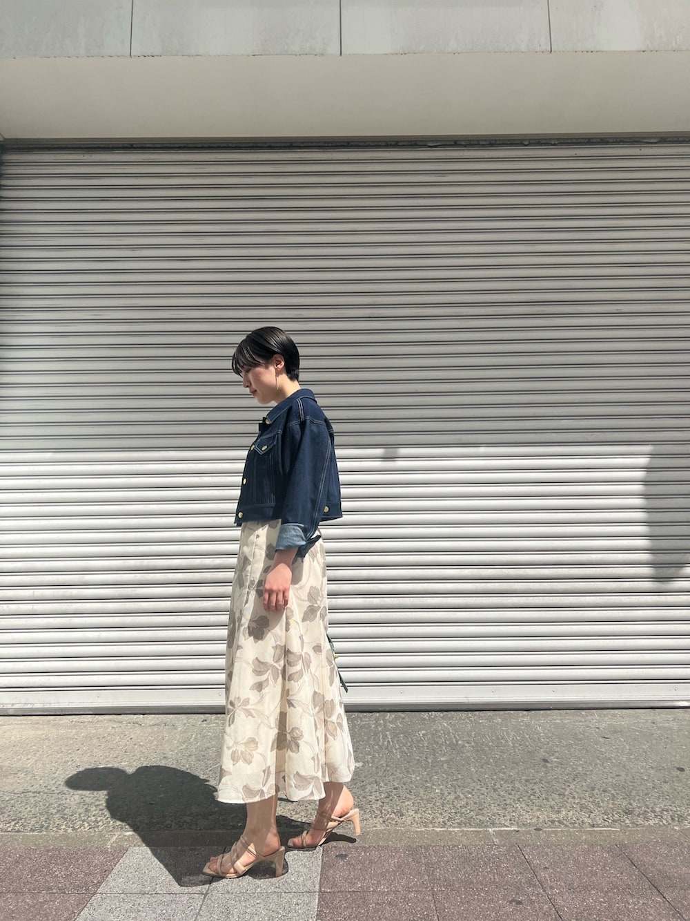 グリーン系のハンドバッグ、ホワイト系のニット/セーター、ベージュ系のサンダルを着用したレディースの春コーディネートの2枚目の写真