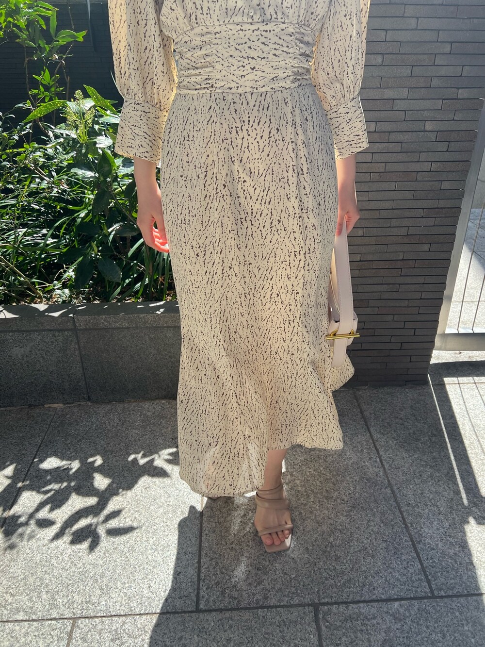 ホワイト系のハンドバッグ、ベージュ系のサンダル、ホワイト系のワンピースを着用したレディースの春コーディネートの10枚目の写真