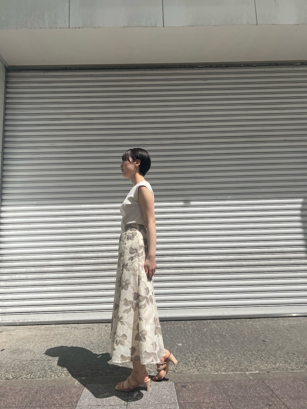 グリーン系のハンドバッグ、ホワイト系のニット/セーター、ベージュ系のサンダルを着用したレディースの春コーディネートの7枚目の写真