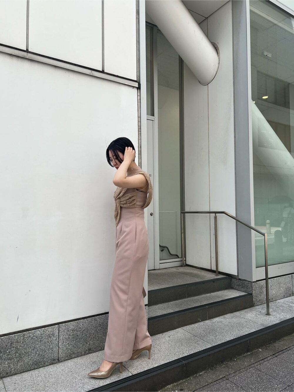 ゴールド系のクラッチバッグ、ベージュ系のパンツドレス、ブラック系のその他トップスを着用したレディースの夏コーディネートの3枚目の写真
