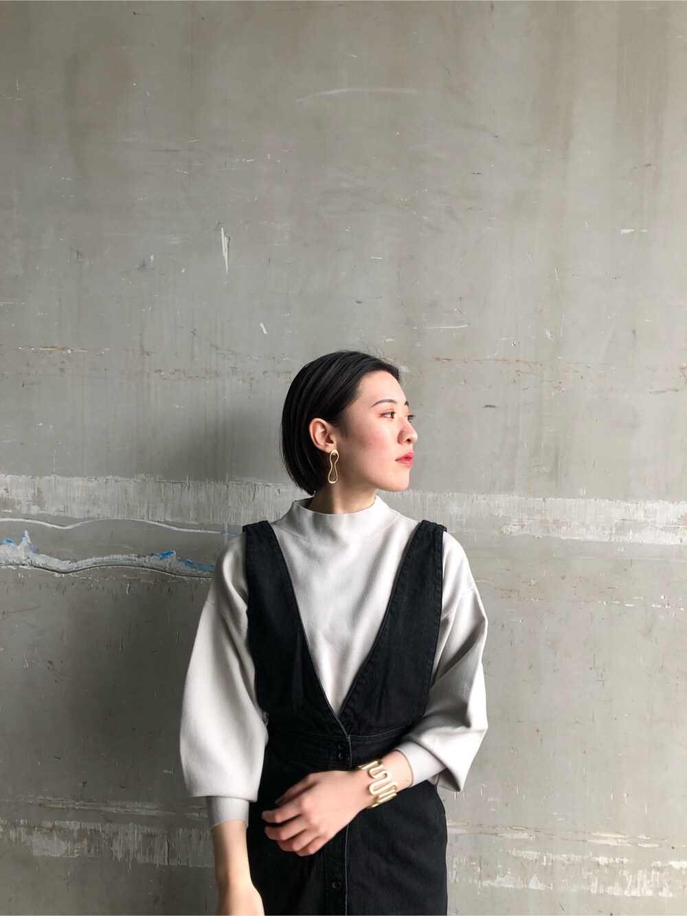 ブルー系のスカート、グレー系のニット/セーター、ゴールド系のピアス（両耳用）を着用したレディースの冬コーディネートの3枚目の写真