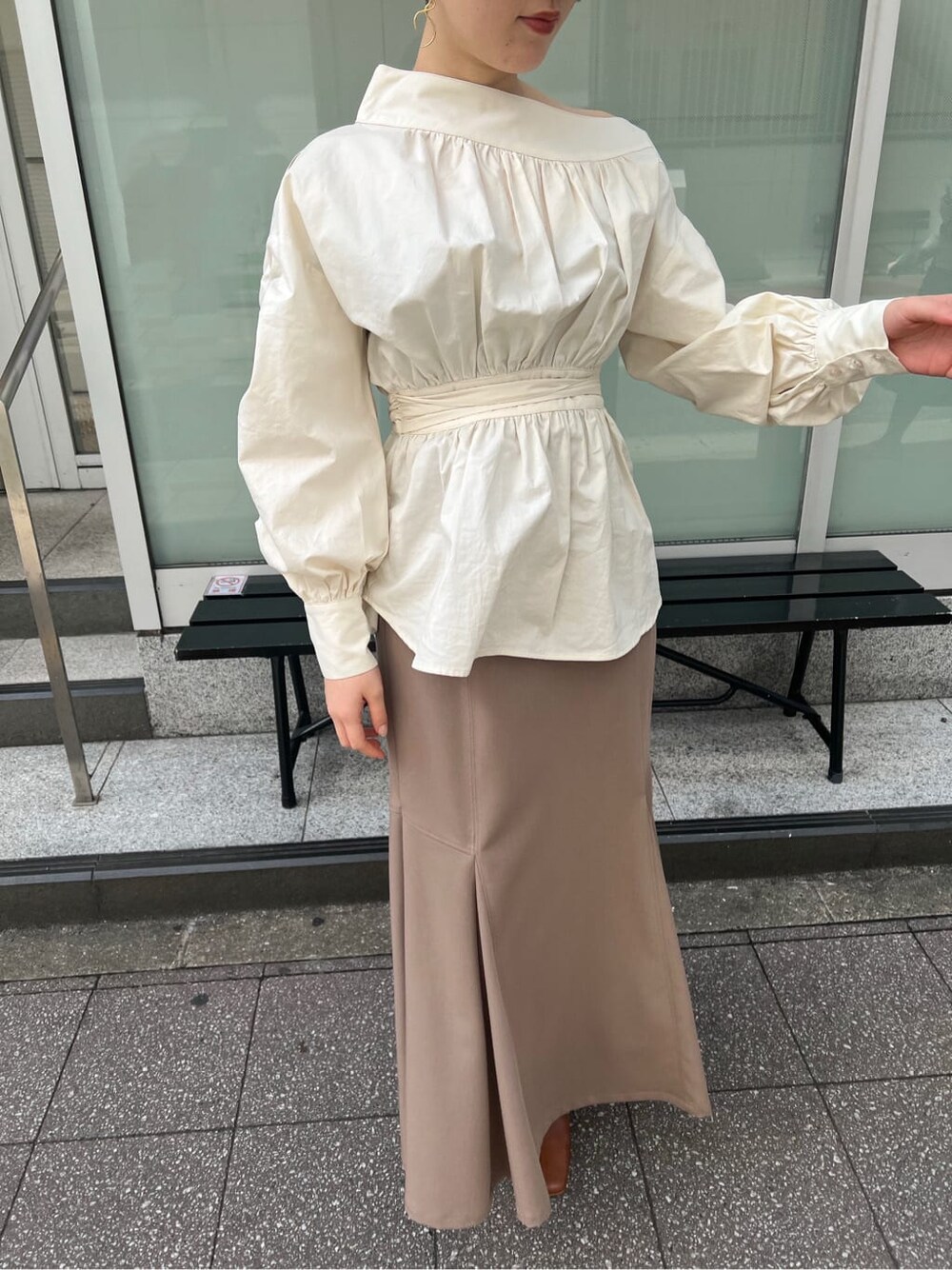 ベージュ系のスカート、ホワイト系のシャツ/ブラウス、ホワイト系のパンプスを着用したレディースの冬コーディネートの2枚目の写真