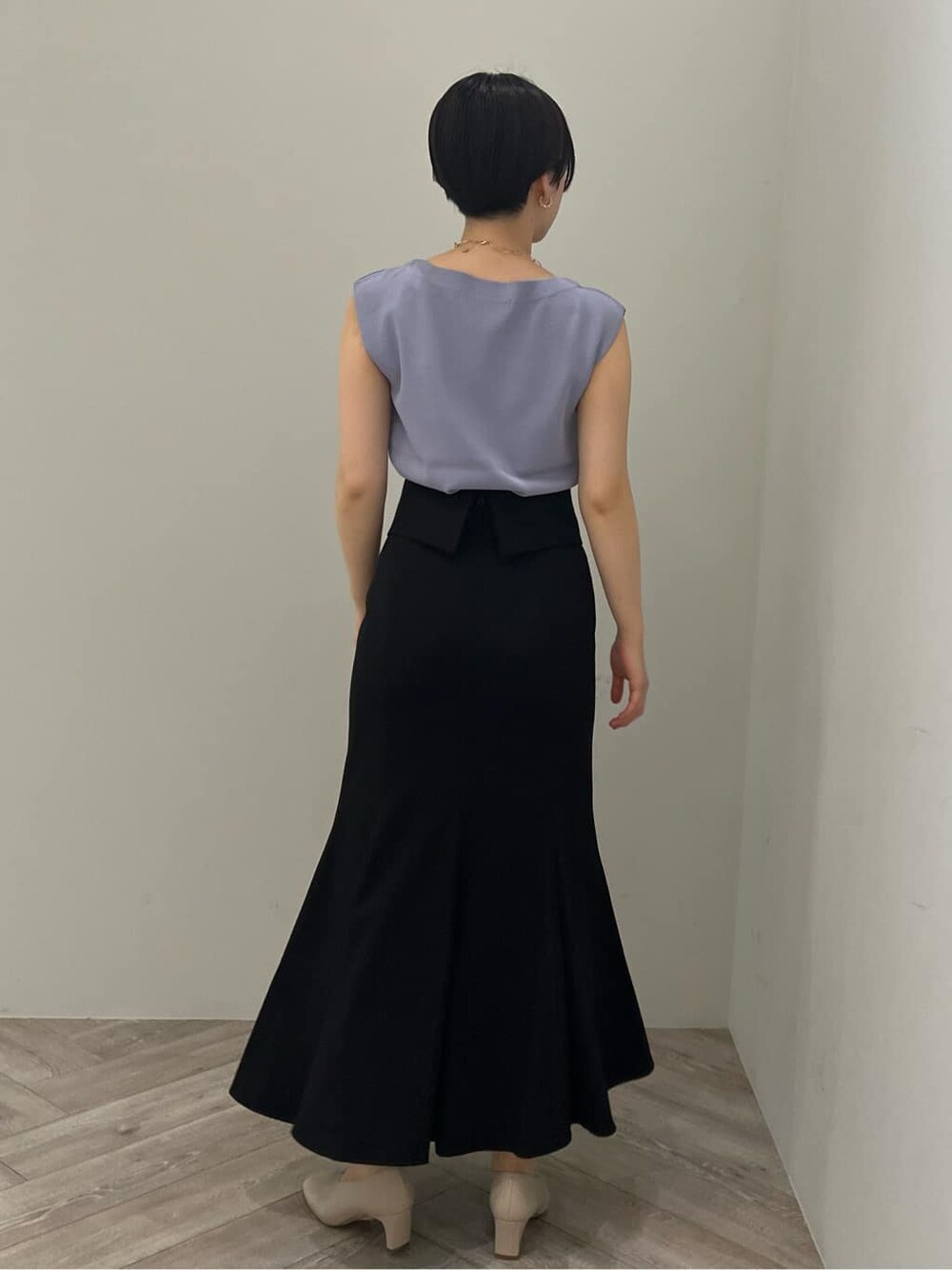 ホワイト系のパンプス、ブラック系のスカート、パープル系のニット/セーターを着用したレディースの夏コーディネートの2枚目の写真