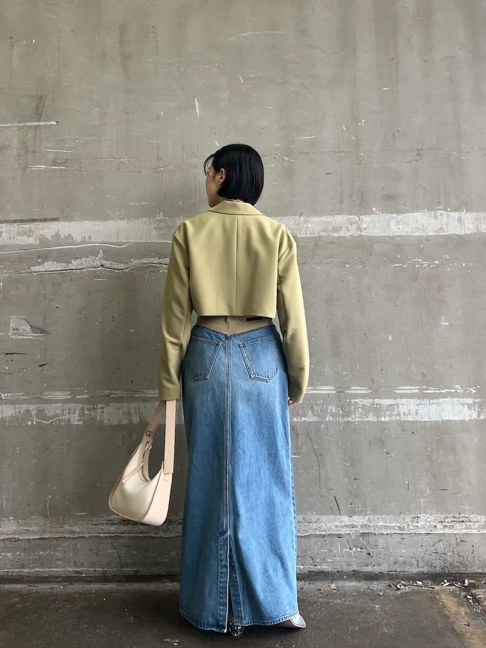 シルバー系のパンプス、グリーン系のテーラードジャケット、グリーン系のデニムスカートを着用したレディースの冬コーディネートの2枚目の写真