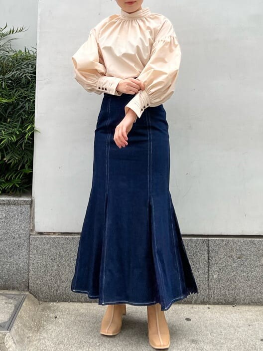 ベージュ系のシャツ/ブラウス、ベージュ系のブーツ、ブルー系のスカートを着用したレディースの春コーディネートの2枚目の写真