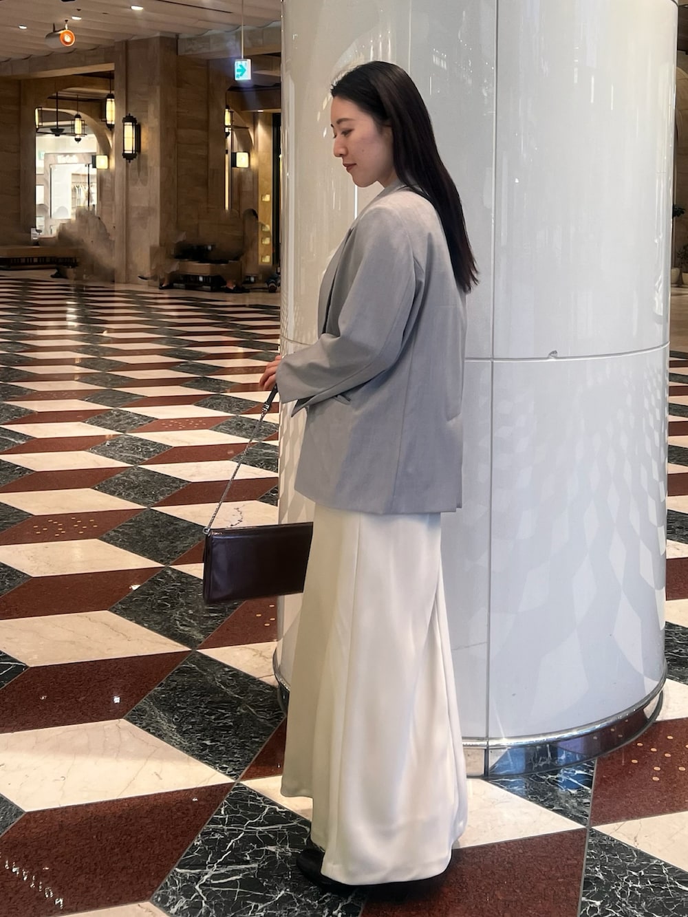 グレー系のテーラードジャケット、イエロー系のドレス、シルバー系のクラッチバッグを着用したレディースの冬コーディネートの2枚目の写真