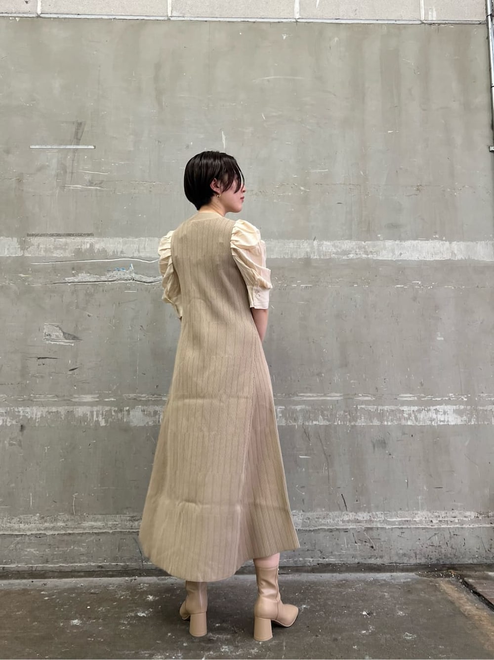 ベージュ系のワンピース、ベージュ系のブーツ、ブラック系のショルダーバッグを着用したレディースの夏コーディネートの3枚目の写真