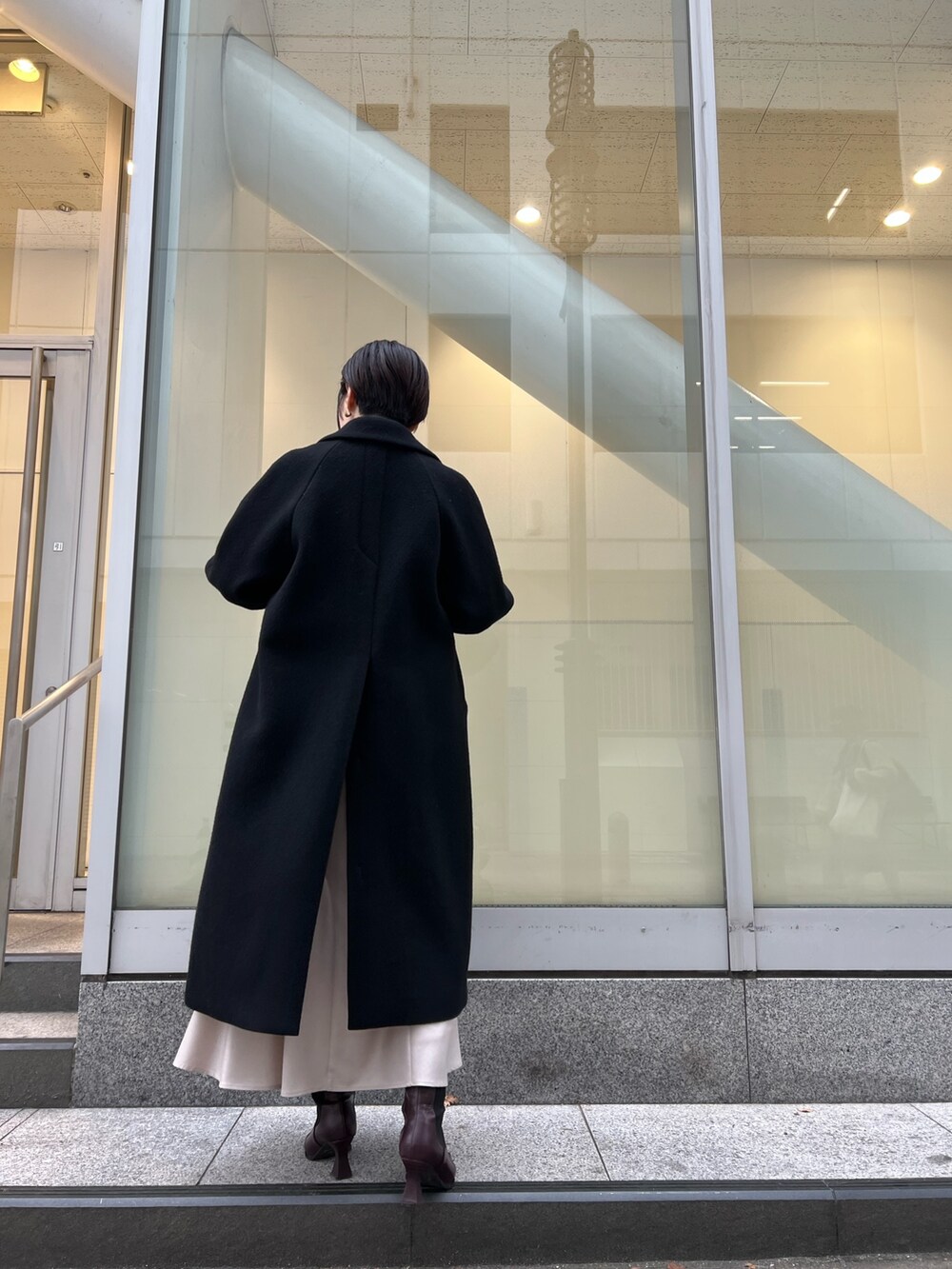 レッド系のブーツ、グレー系のスカート、ブラック系のその他アウターを着用したレディースの冬コーディネートの3枚目の写真