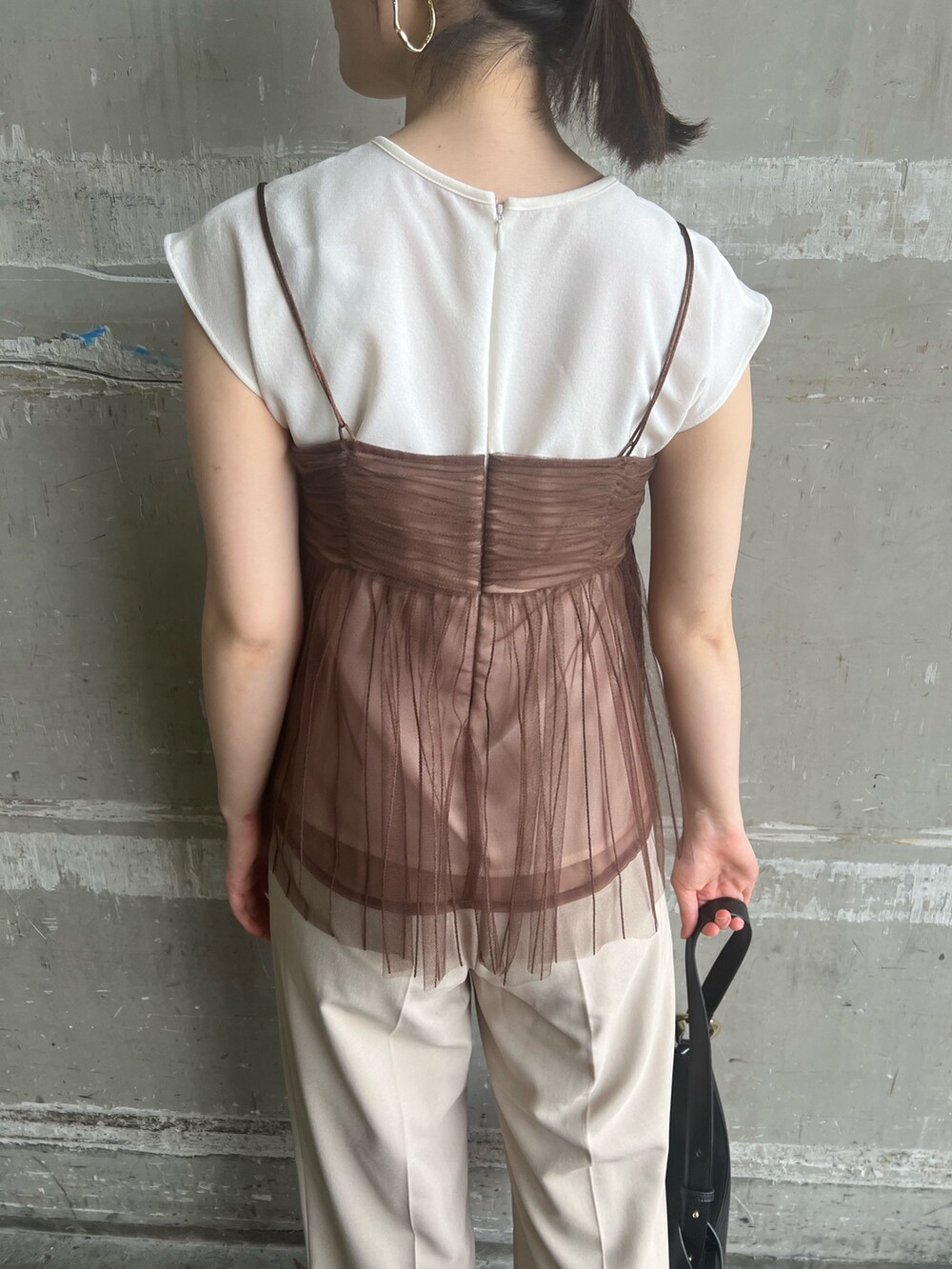 ブラック系のサンダル、ブラック系のショルダーバッグ、ホワイト系のスラックスを着用したレディースの夏コーディネートの6枚目の写真