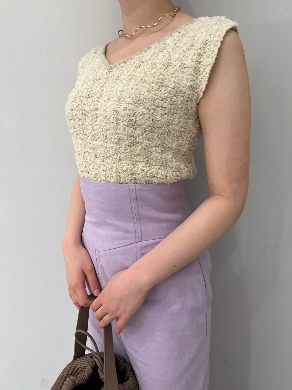 ホワイト系のハンドバッグ、ホワイト系のニット/セーター、パープル系のスカートを着用したレディースの春コーディネートの6枚目の写真