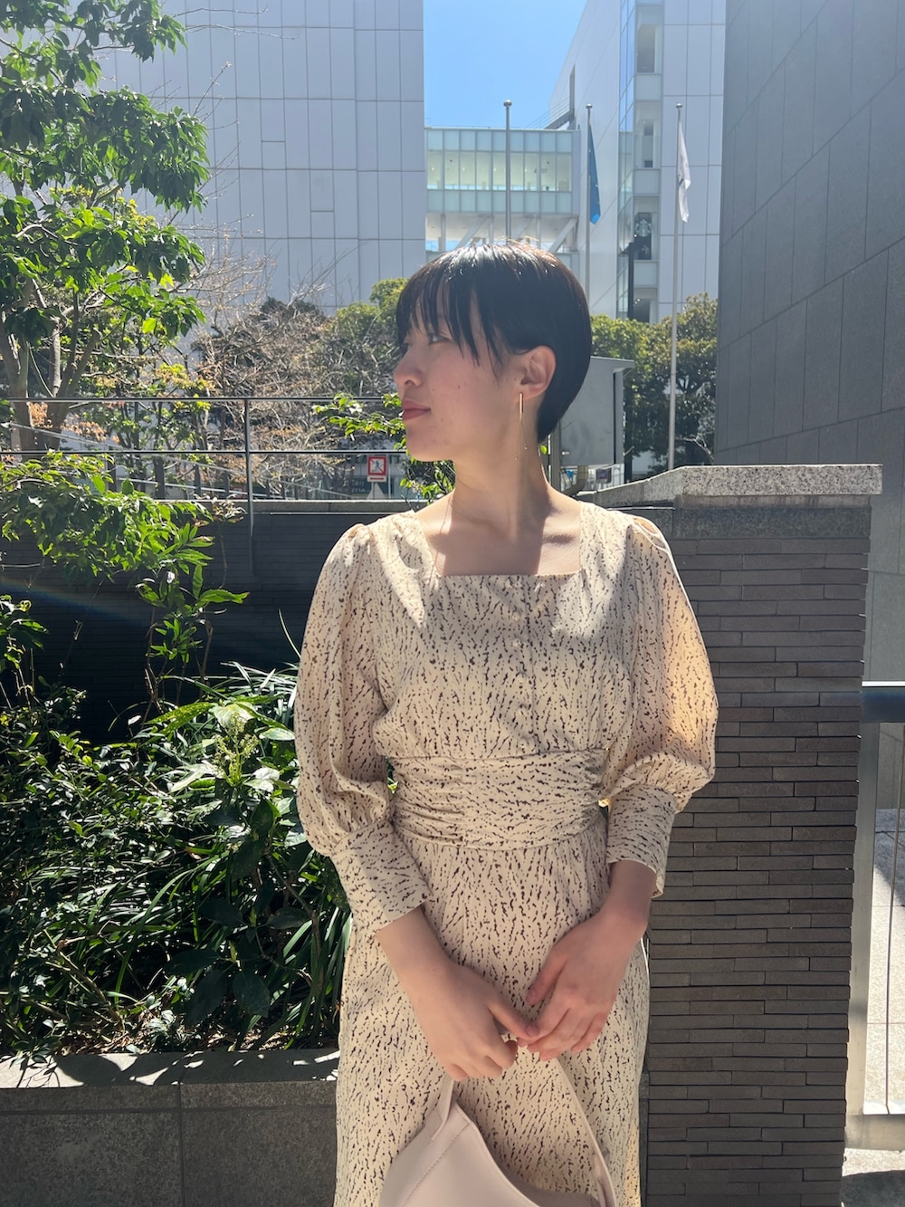 ホワイト系のハンドバッグ、ベージュ系のサンダル、ホワイト系のワンピースを着用したレディースの春コーディネートの7枚目の写真