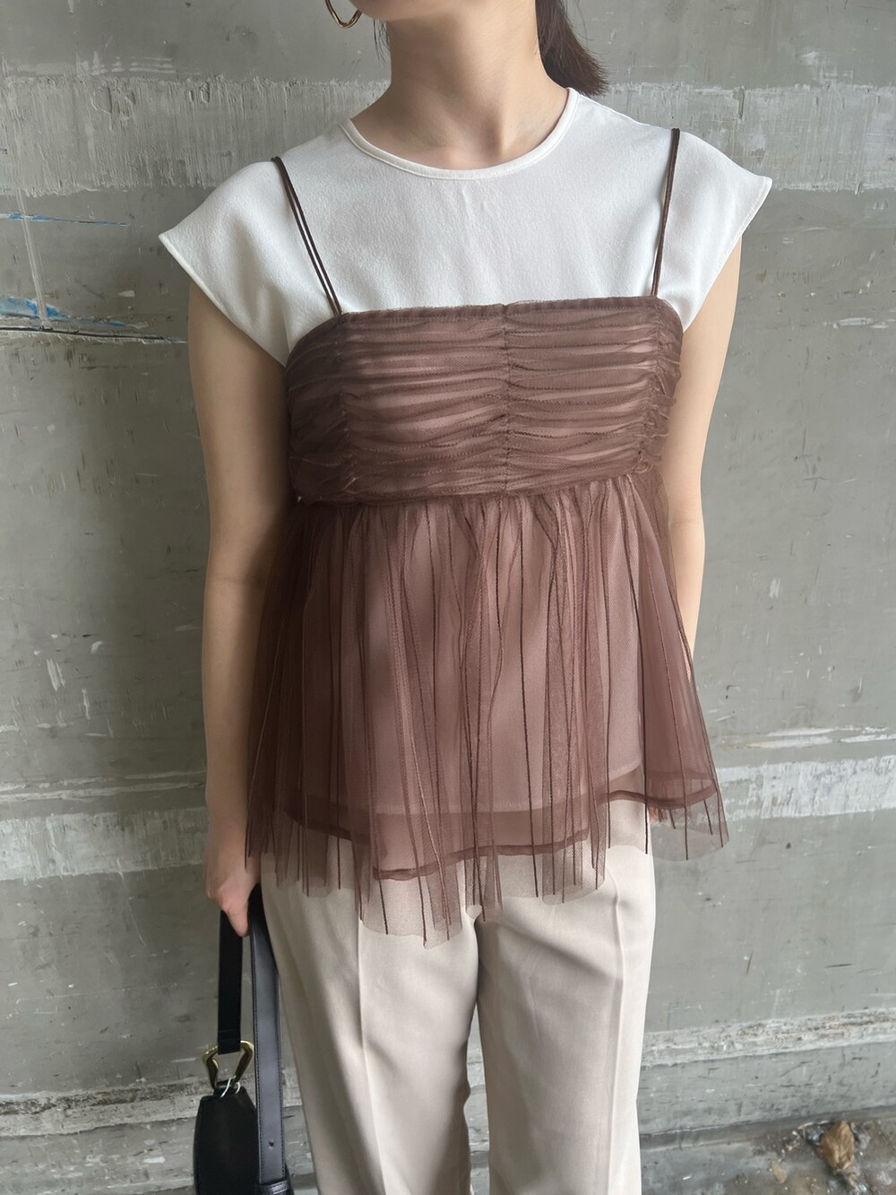 ブラック系のサンダル、ブラック系のショルダーバッグ、ホワイト系のスラックスを着用したレディースの夏コーディネートの5枚目の写真