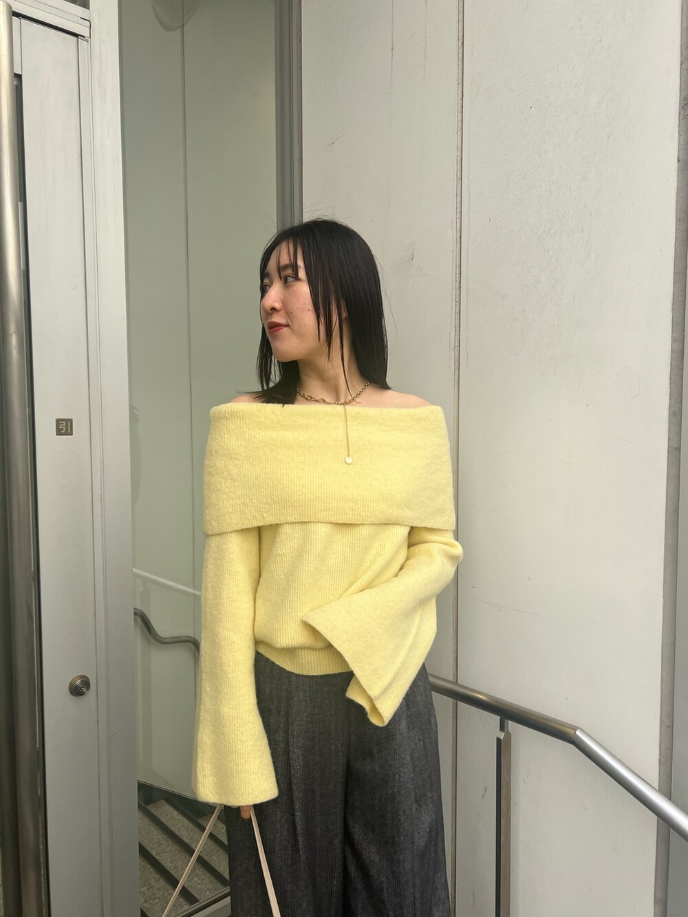 イエロー系のニット/セーター、ブラック系のブーツ、グレー系のその他パンツを着用したレディースの冬コーディネートの4枚目の写真