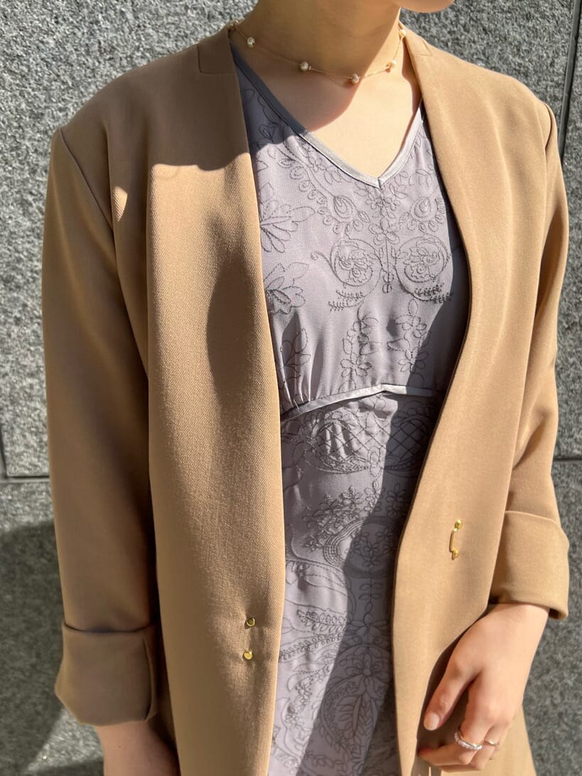 ブラウン系のクラッチバッグ、ベージュ系のその他アウター、パープル系のドレスを着用したレディースの冬コーディネートの10枚目の写真