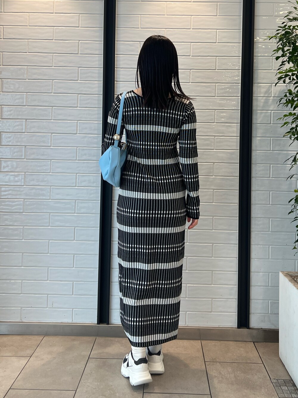 ブルー系のショルダーバッグ、ブラック系のワンピース、グレー系のスニーカーを着用したレディースの冬コーディネートの2枚目の写真