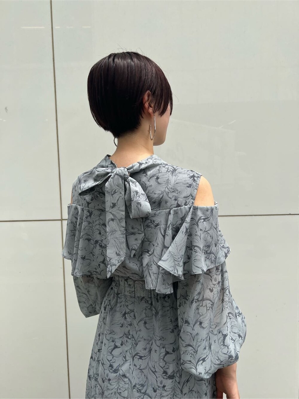 ベージュ系のハンドバッグ、ブルー系のワンピース、シルバー系のピアス（両耳用）を着用したレディースの夏コーディネートの5枚目の写真