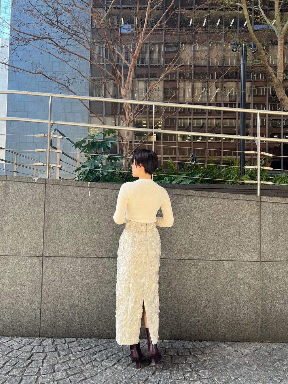 グレー系のカーディガン/ボレロ、ベージュ系のスカート、ホワイト系のニット/セーターを着用したレディースの冬コーディネートの4枚目の写真