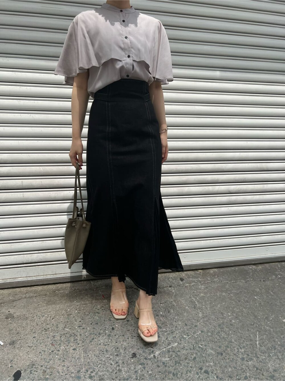 ベージュ系のハンドバッグ、ブラック系のスカート、その他のサンダルを着用したレディースの夏コーディネートの6枚目の写真