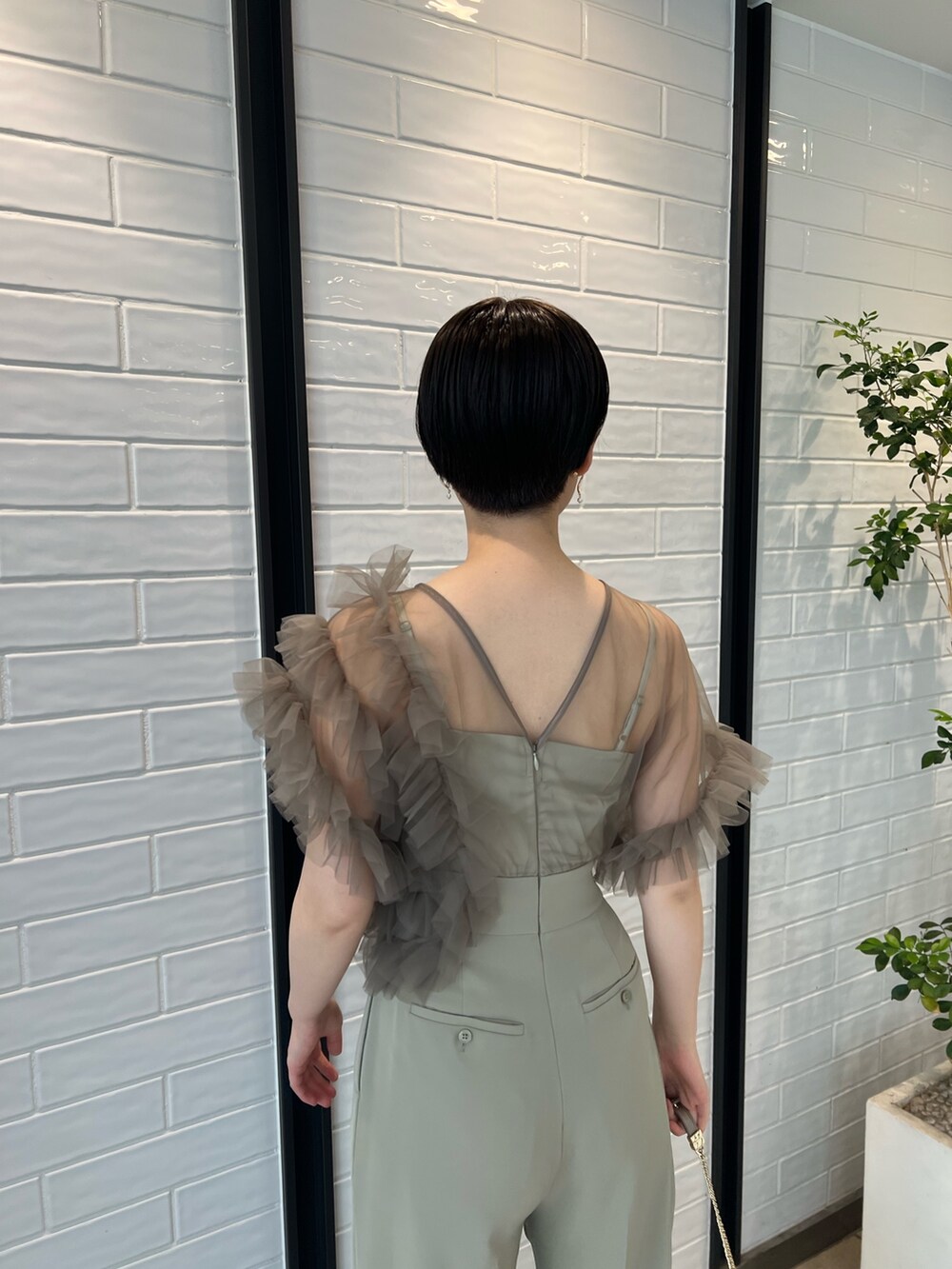 シルバー系のパンプス、シルバー系のハンドバッグ、グリーン系のパンツドレスを着用したレディースの春コーディネートの5枚目の写真