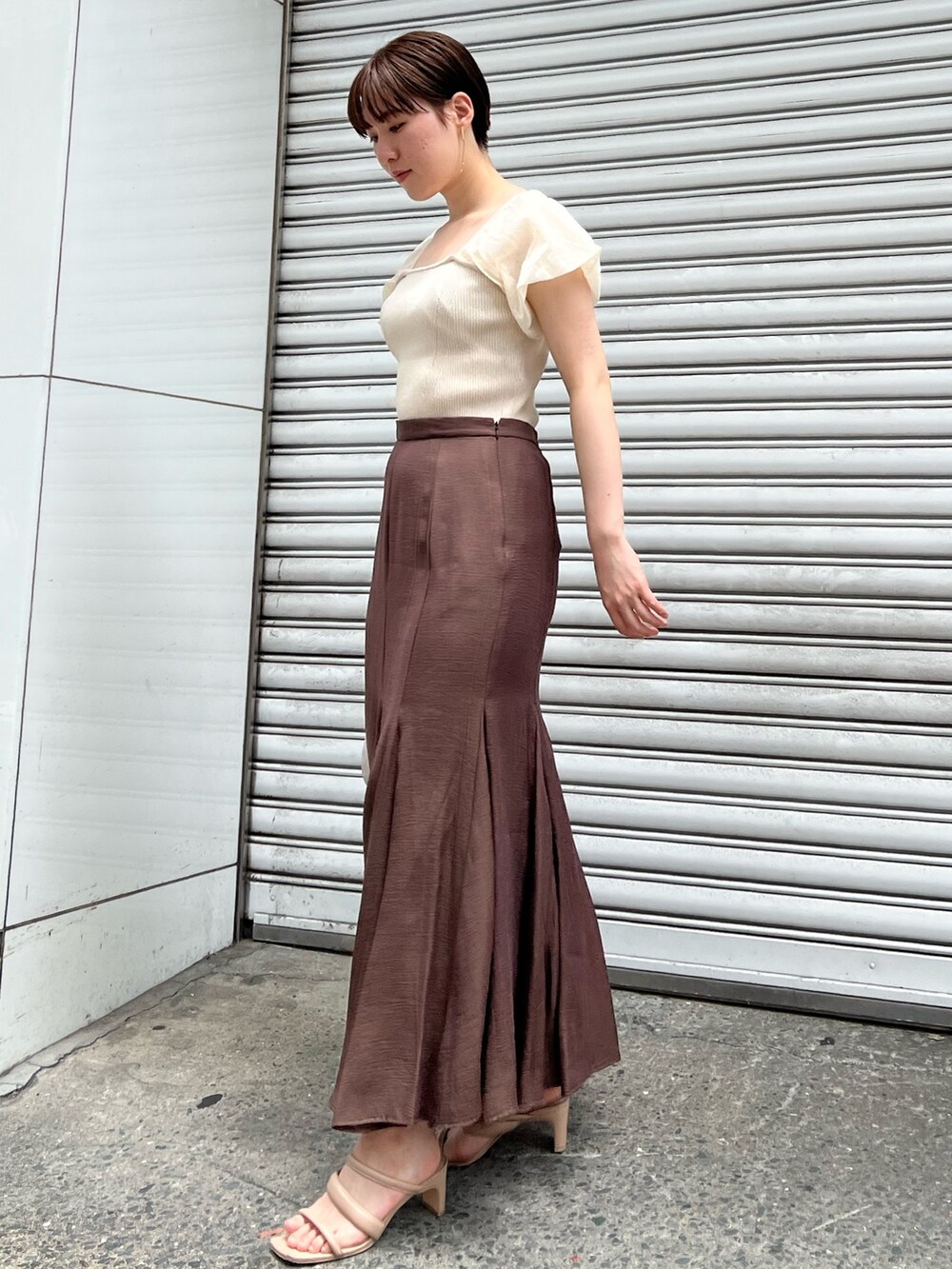 ベージュ系のサンダル、ブラウン系のスカート、ホワイト系のハンドバッグを着用したレディースの夏コーディネートの2枚目の写真