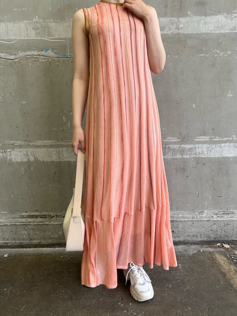 ホワイト系のスニーカー、ベージュ系のハンドバッグ、オレンジ系のワンピースを着用したレディースの春コーディネートの5枚目の写真