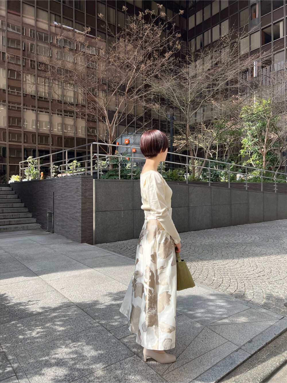 イエロー系のその他アウター、ベージュ系のスカート、ホワイト系のニット/セーターを着用したレディースの冬コーディネートの5枚目の写真