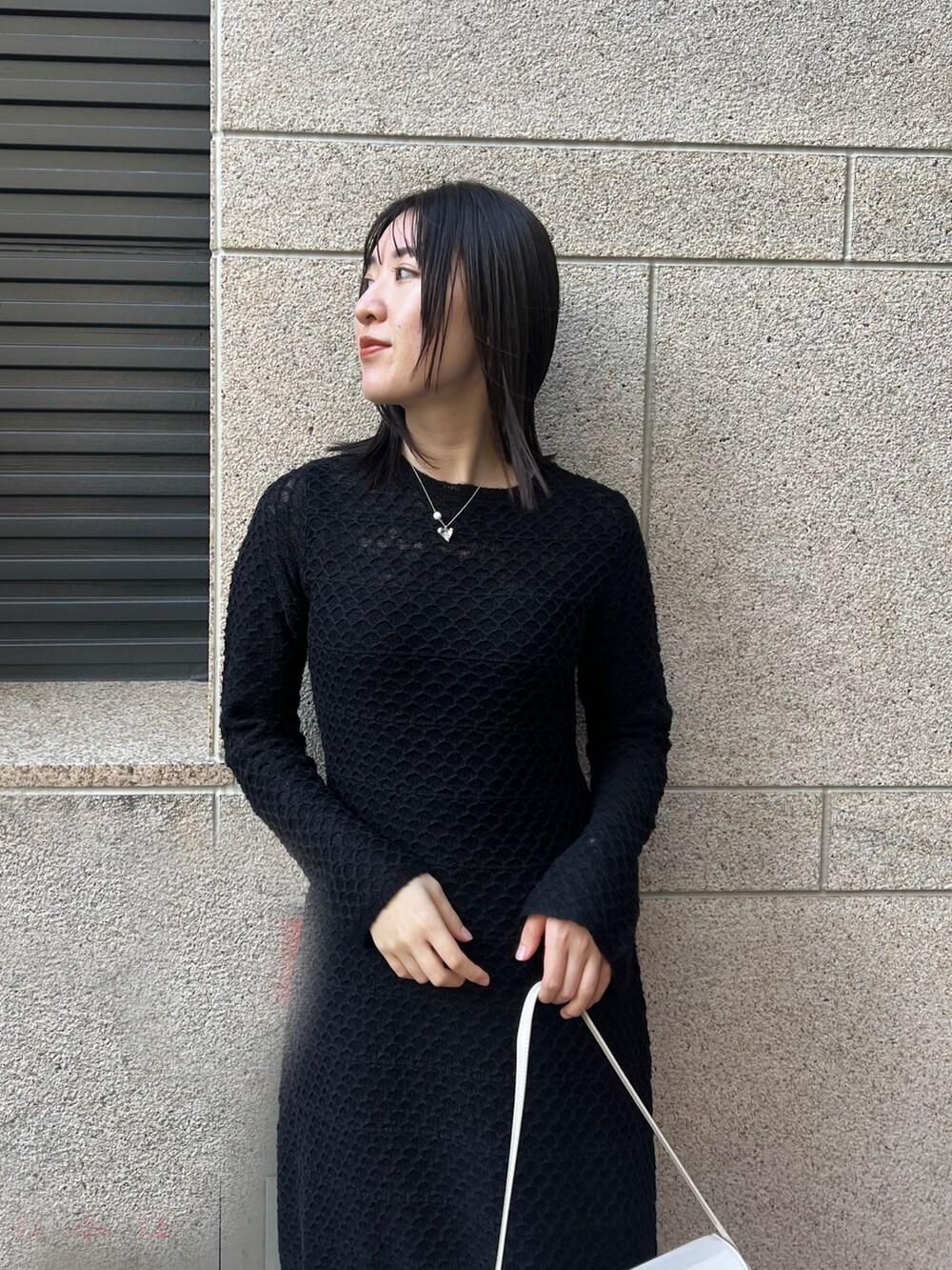 ブラック系のブーツ、ブラック系のワンピース、ホワイト系のショルダーバッグを着用したレディースの秋コーディネートの3枚目の写真