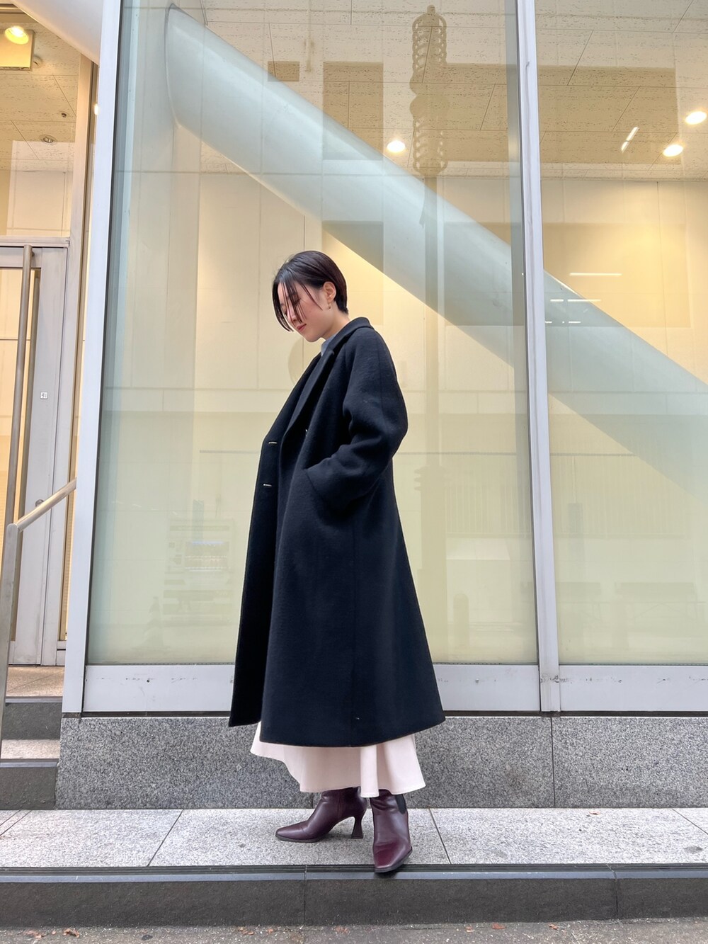 レッド系のブーツ、グレー系のスカート、ブラック系のその他アウターを着用したレディースの冬コーディネートの2枚目の写真