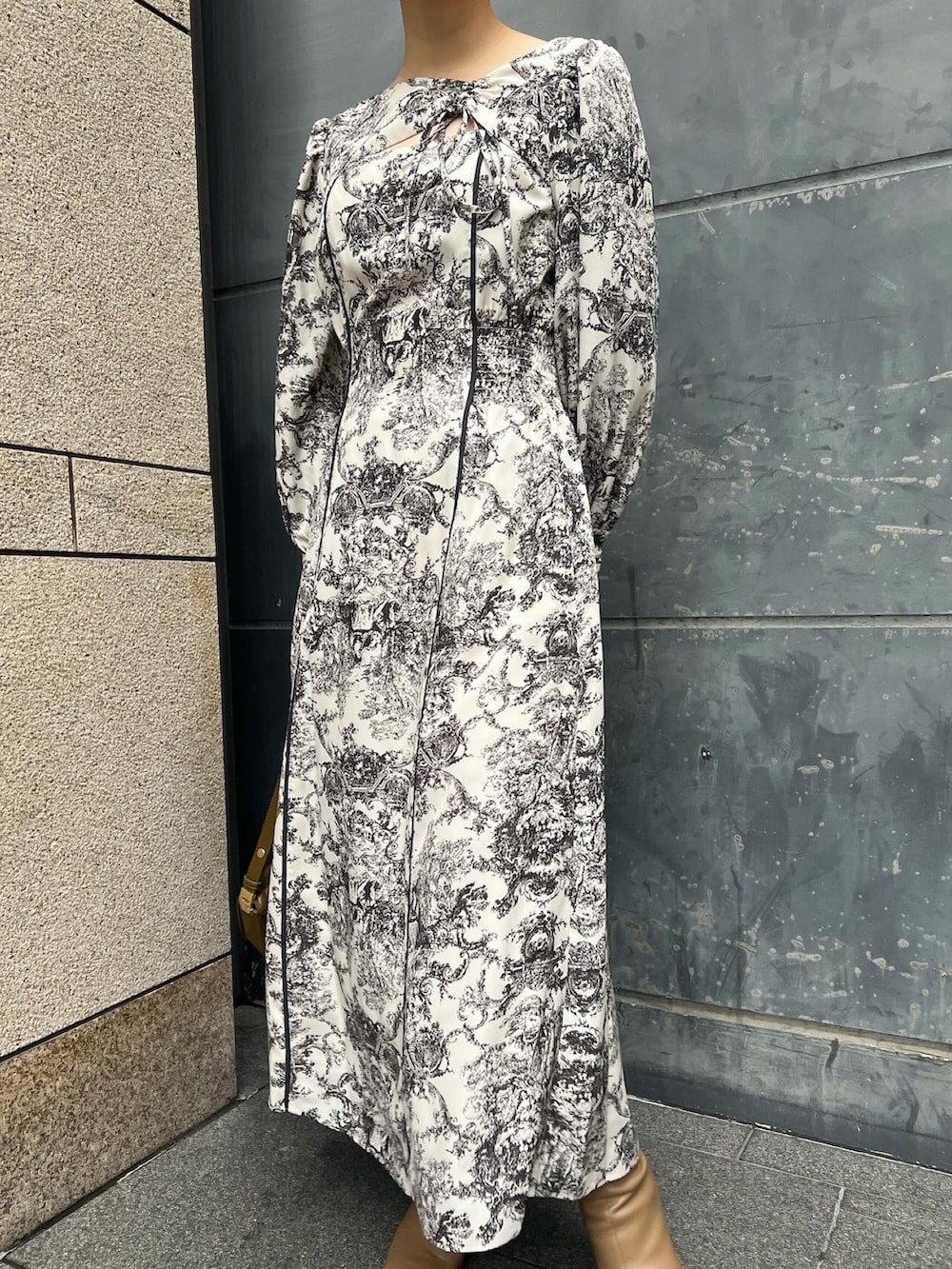 ホワイト系のノーカラーコート、ホワイト系のワンピース、ベージュ系のブーツを着用したレディースの冬コーディネートの4枚目の写真