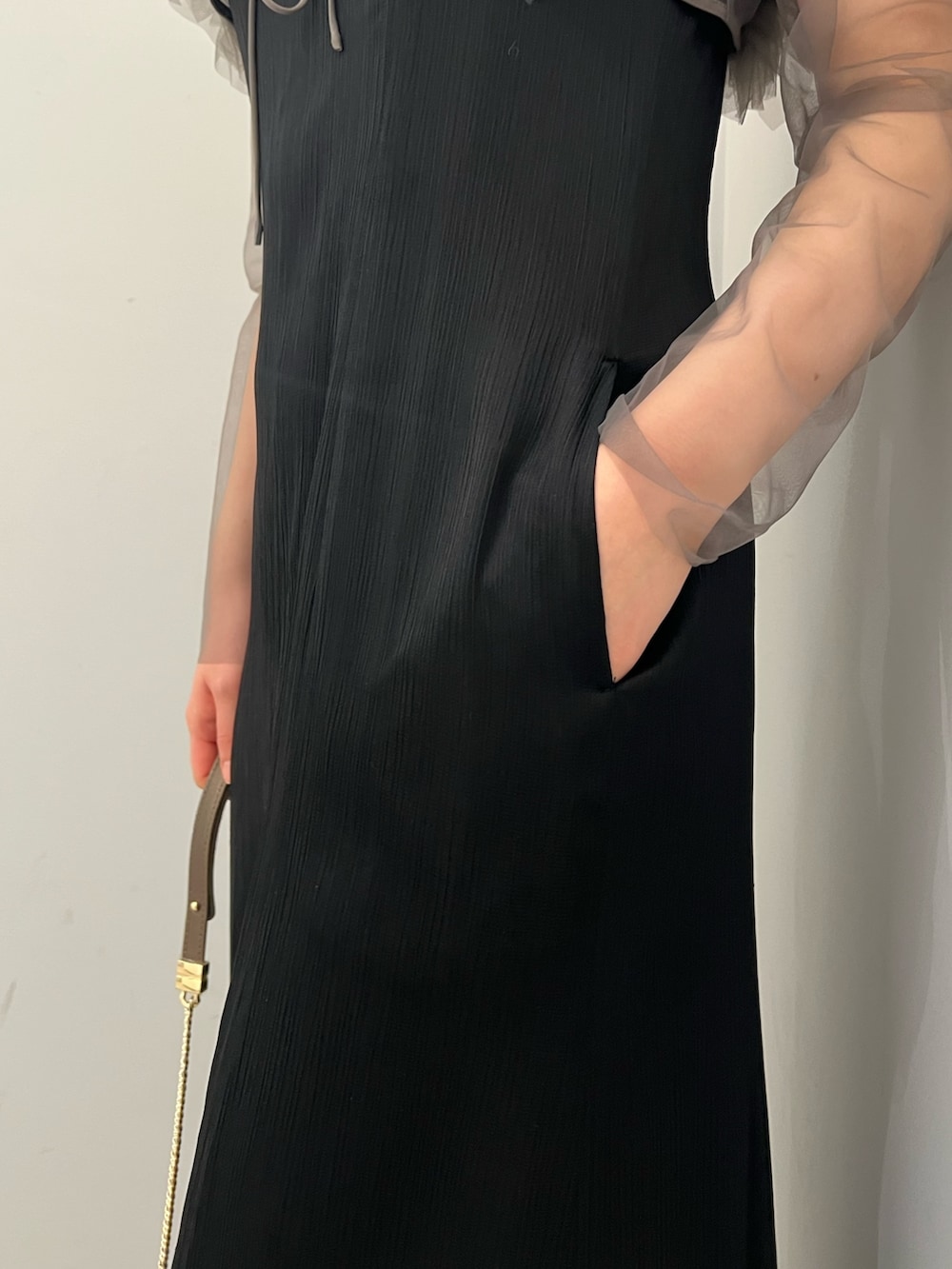 グレー系のドレス、ゴールド系のクラッチバッグ、ゴールド系のパンプスを着用したレディースの春コーディネートの8枚目の写真