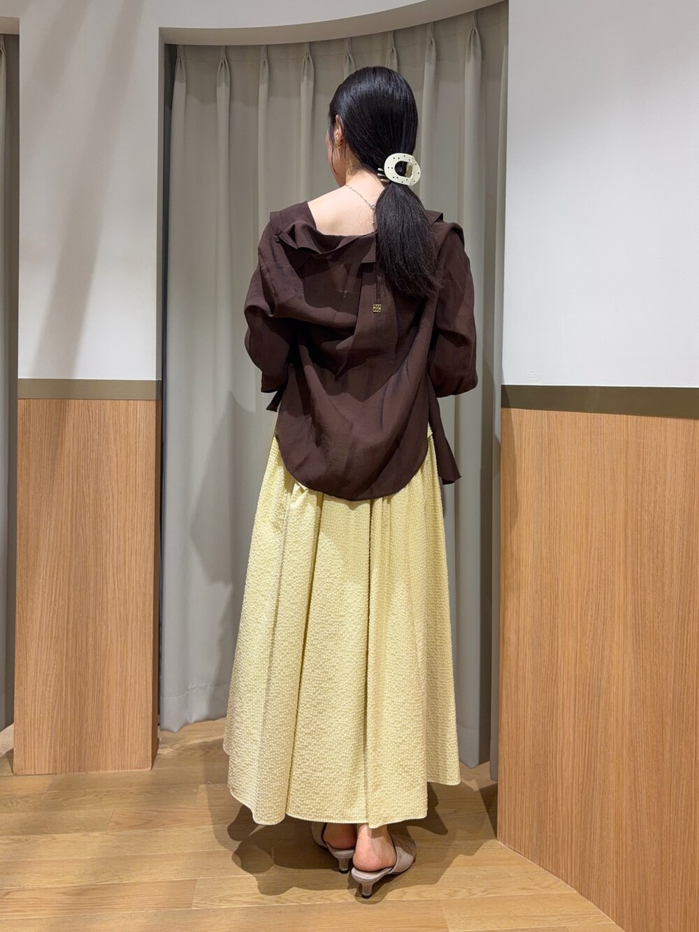 イエロー系のワンピース、ブラウン系のシャツ/ブラウス、ベージュ系のサンダルを着用したレディースの夏コーディネートの2枚目の写真