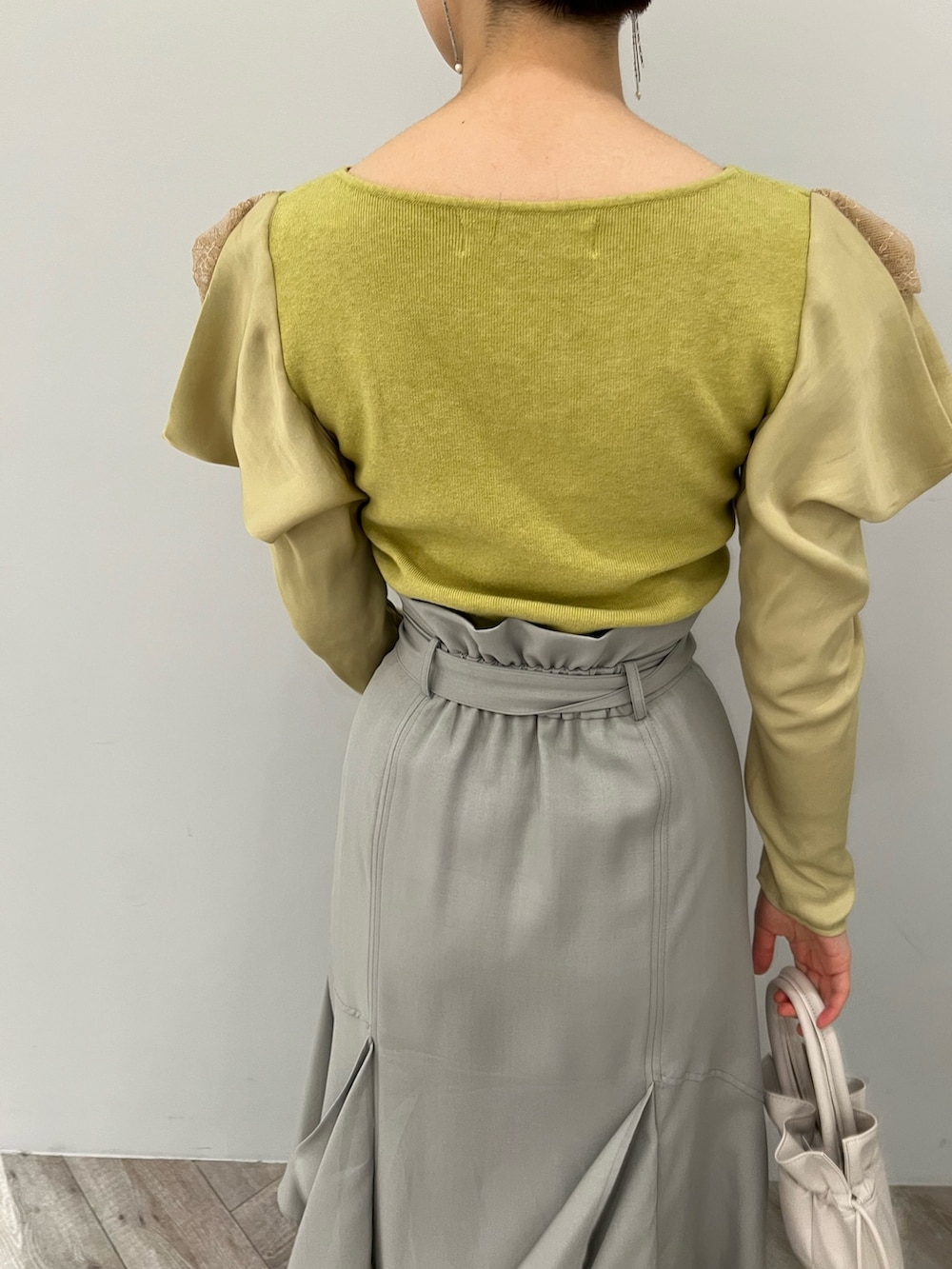 ブラック系のブーツ、ホワイト系のハンドバッグ、グリーン系のスカートを着用したレディースの冬コーディネートの6枚目の写真