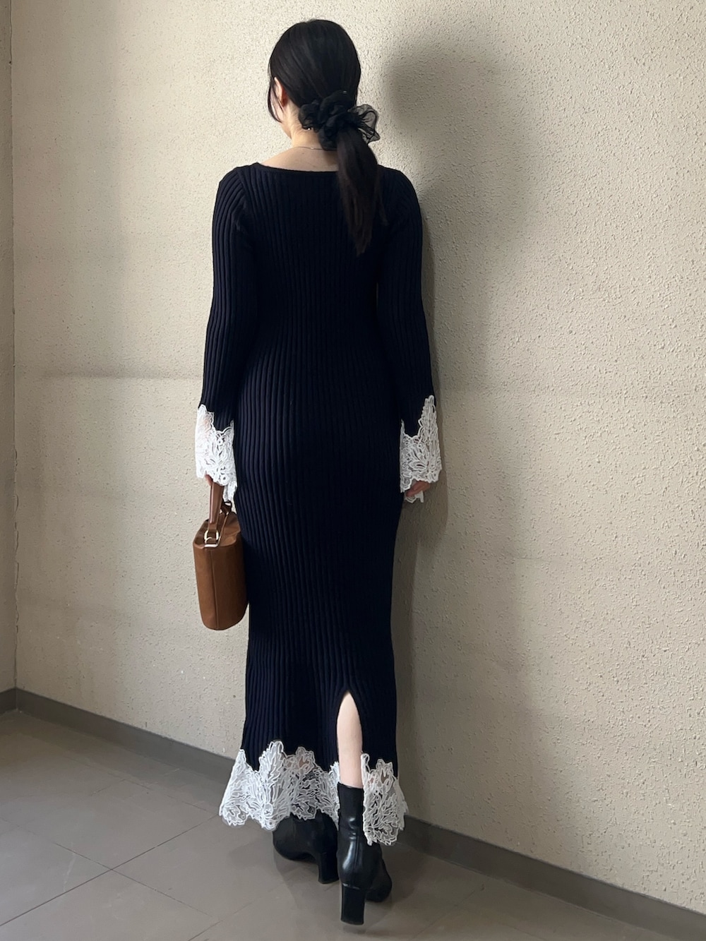 イエロー系のハンドバッグ、ブルー系のワンピース、ブラック系のブーツを着用したレディースの秋コーディネートの3枚目の写真